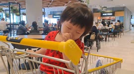 Baby girl tries to fight sleep in shopping trolley