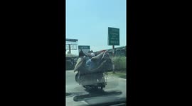Wow! This man balances his motorbike while carrying it on his own motorbike on the street in Vietnam