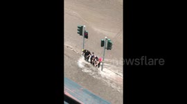Athens locals desperately try to keep balance crossing road as floods turn streets into rivers