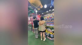 Arcade-goer pitches ball hard to hit prize... only for it to bounce back to his face