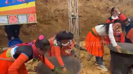 Women using their hands to dry green tea on a hot pan during the tea festival