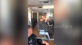 Barber hit by powercut honours appointments by cutting customers' hair in the street
