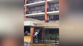 Students climb on railings to cross flooded road