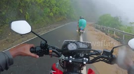 Landslide blocks motorcycle riders on mountain road during typhoon in the Philippines
