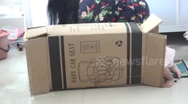 A cute 1 year old toddler is having great fun with a cardboard box, that her baby car seat was packaged in.