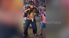 Tourist dances with street performer in Bangkok's Chinatown