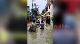 Firefighters carry elderly locals on their backs through submerged streets in northern India