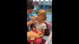 Little girl bravely sits through the ear piercing without any extreme reaction