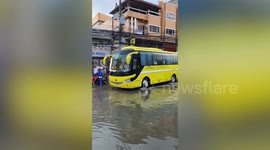 Stranded commuters and motorists cheer as bus crosses over flooded road