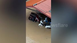 Locals push motorcycles through knee-deep flood in Thailand