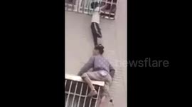 Heroic Chinese man climbs two floors to hold up trapped toddler for 10 minutes