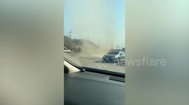 Dust devil tornado whips through dirty car park