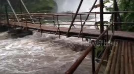 Flash flood surges under wooden bridge as torrential rain batters Thai national park
