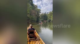 Boatman plunges into water while pushing bamboo raft with tourists