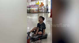 Toddler shakes vigorously sitting on vibrating exercise machine