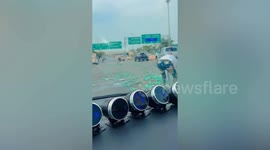 Motorists help pick up fallen milk boxes that blocks traffic along road