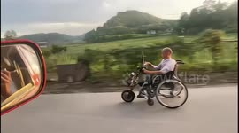 Elderly Chinese man drives modified electric wheelchair along road