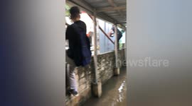 Schoolboys clamber across wall to avoid flooded path