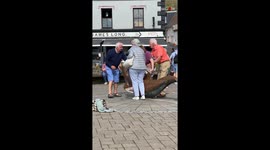 Elderly woman draws audience around her from her laughing fit while trying to get off a statue