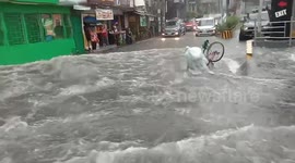 Flash flood knocks over cyclist as deluge swamps road in the Philippines