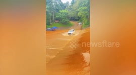 Brave drivers power through raging flood torrents flowing over reservoir