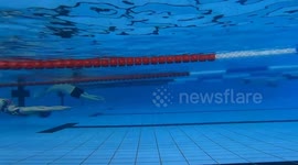 Swimmer glides along pool's bottom to avoid crowded surface