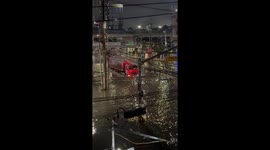 Lad hangs on the back of truck driving through flooded road
