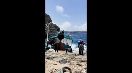 Fearless locals unload goods from ship during choppy seas