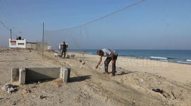 Man removes a bird caught in his net on the shore of the Mediterranean Sea in Gaza, Palestine