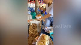 Squirrel tries to steal fruit from customers eating at stall