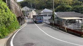 Bus drivers skillfully pass by each other on tight curved road in Japan