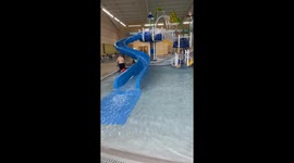 Lively girl is all smiles following a hilarious wipeout on slick water slide