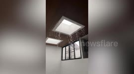 Rain pours through leaky roof onto floor below