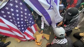 People burn American and Israeli flags at the rally to Defend Palestine in Jakarta, Indonesia