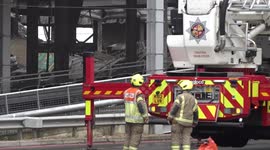 Workers assess damage to fire-stricken multi-storey car park at Luton Airport in UK