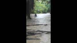 Neighbours help carry motorcycle across deluge