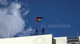 Free Palestine chants at Piccadilly Circus with flag of Palestine flying on the roof of Trocadero