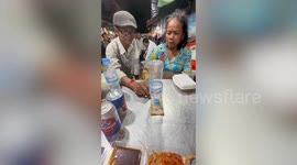 Grandmother joyfully waves arms when she wins paper-pulling-under-bottle game