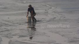 Indonesian fishermen use makeshift surfboards to glide over thick mud