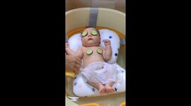 Baby enjoys relaxing bath with cucumbers covering eyes and nipples