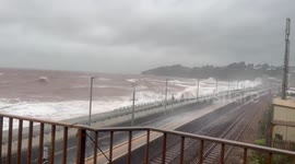 Waves crash over onto passing train in Devon as Storm Babet hits UK