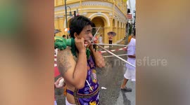 Devotee joins procession while gigantic skewers stick out of his face during Thai Vegetarian Festival