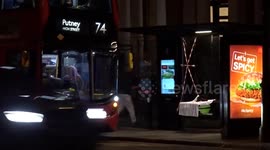 Bizarre green suitcase with two wigs on it left inside a bus stop on Cromwell Road in London - across the road view