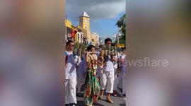 Local carries pineapples on long skewer impaled through his face during Thai Vegetarian Festival