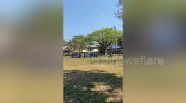 School kids have fun chasing dust devil tornado on field
