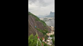 Slackliner balances on springy rope overlooking Brazil's Sugarloaf Mountain