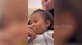 Toddler keeps twisting her dummy while sitting in mother's lap