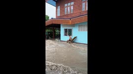 Shirtless husband sits in chair as raging flood torrents lash home