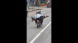 Motorcycle pillion passenger carries scooter on the back of bike