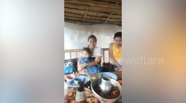 Family carry on eating dinner as storm lashes their table